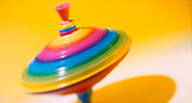 spinning rainbow colored top on a yellow background